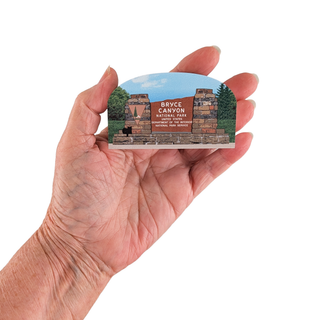 Hand holding a small 3/4" wooden cut out replica of   Bryce Canyon National Park design