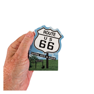 Hand holding a 3/4" thick wood Route 66 sign with a scenic background
