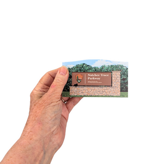 Hand holding a 3/4" thick wooden cutout with Natchez Trace Parkway sign
