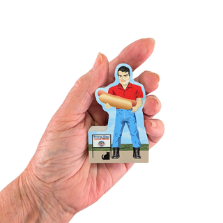 Hand holding a 3/4" thick wood cutout of a person in a red shirt and blue pants with a hot dog.