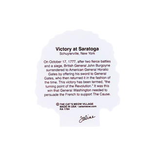 back of product with text about George Washington's profile, containing the text 'Victory at Saratoga' and a historical paragraph about the battle. Small text at the bottom reads 'The Cat's Meow Village Made in USA catsmeow.