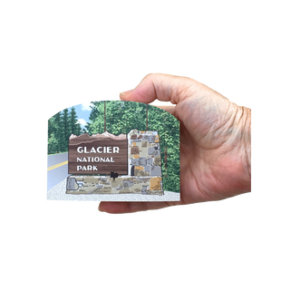 Hand holding a 3/4" thick wooden illustration of a Glacier National Park sign with a scenic background