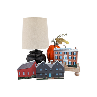 Decorative table setting with a lamp, pumpkins, and small buildings on a white background