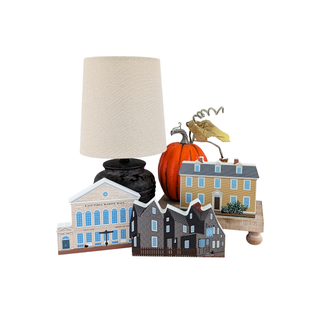 Decorative set with a lamp, pumpkins, and small buildings on a white background