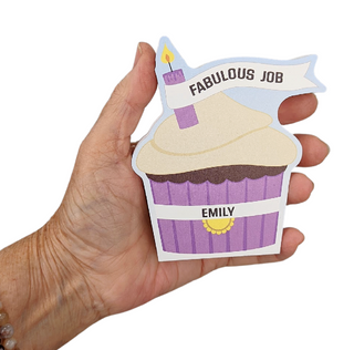 Hand holding a wooden replica with a cupcake design and 'Fabulous Job' text.