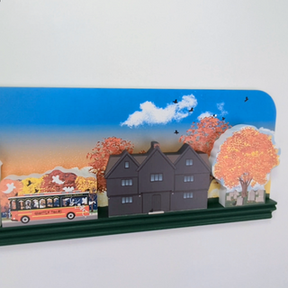 Model of a house with trees and a bus on a white background