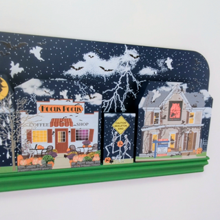 Halloween-themed display with a coffee shop and haunted house design on a white background