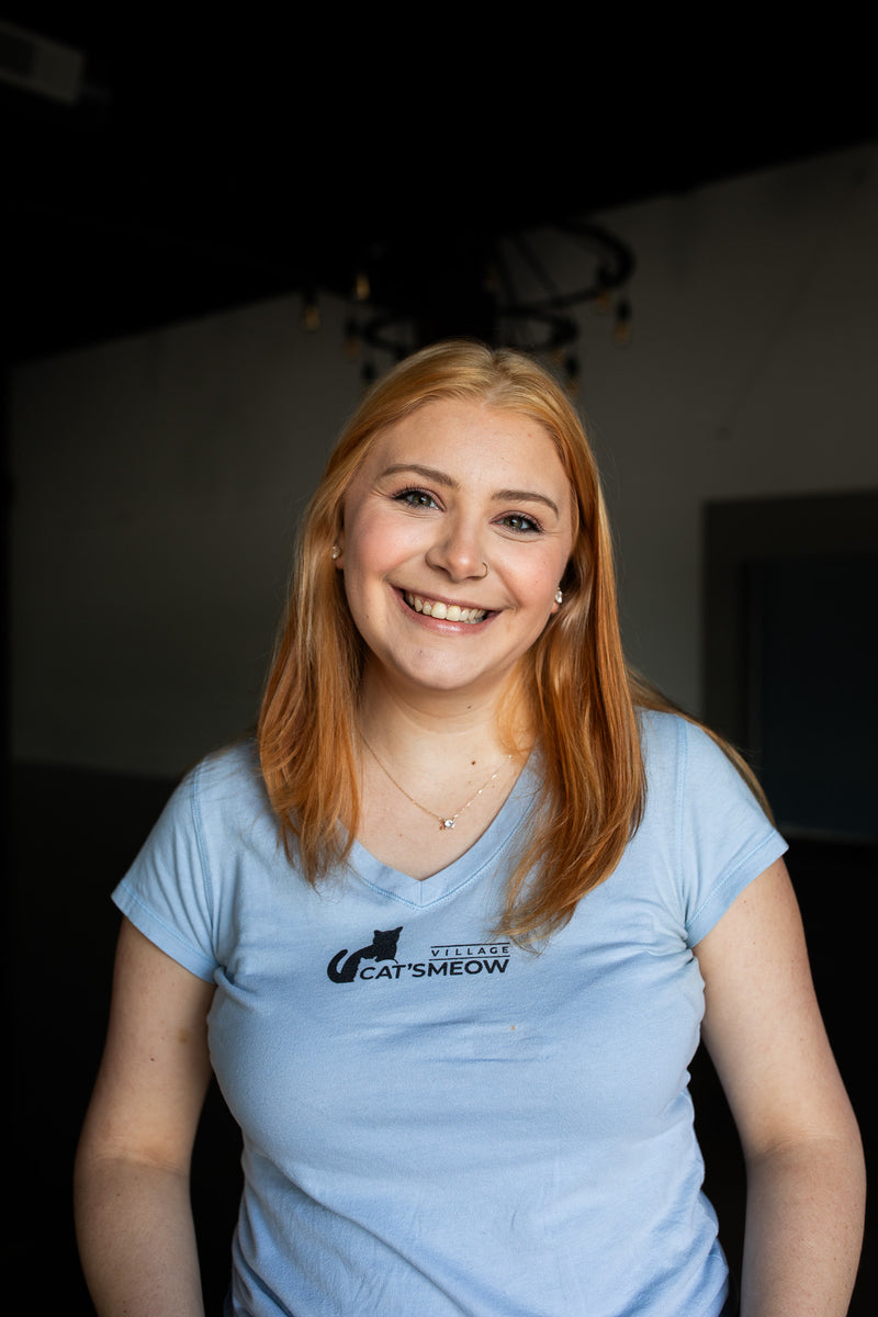 Person wearing a light blue t-shirt with a logo, sitting indoors.