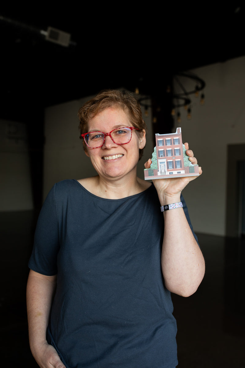 Person holding a small model of a building indoors