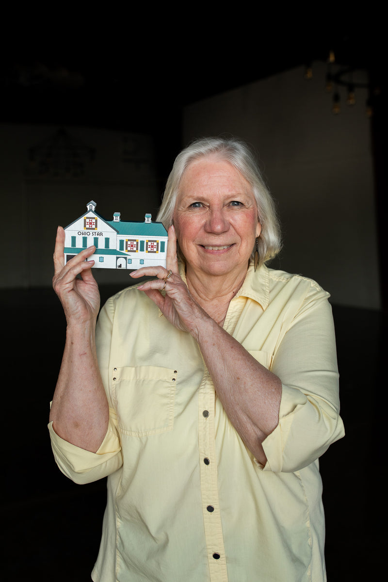 Woman holding a small model of a house against a dark background