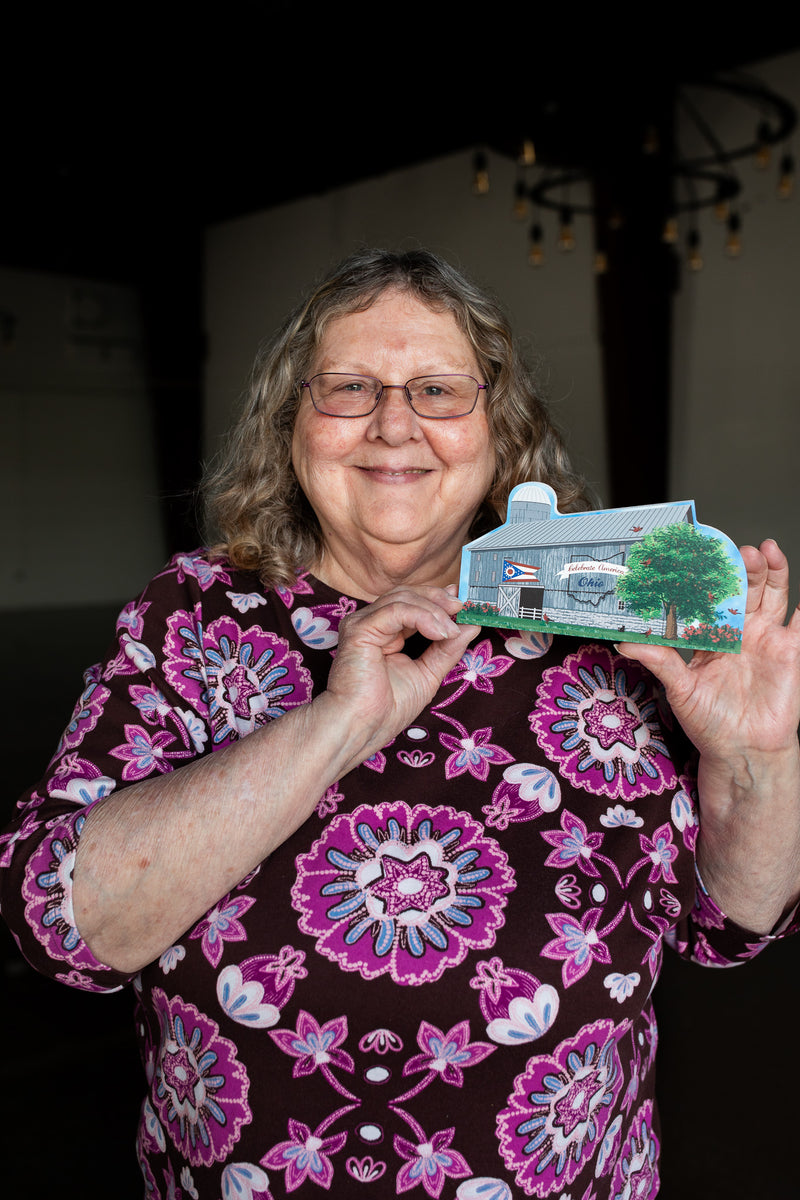 Woman holding a small model of a house with a garden.