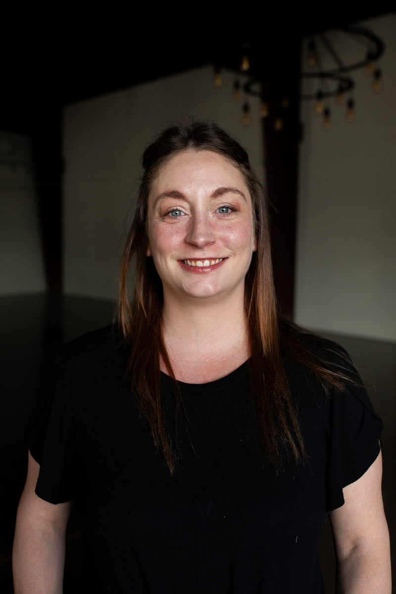 Woman wearing a black shirt in a dimly lit room with a chandelier.