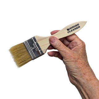 Hand holding a paintbrush with 'House Cleaner' text on a white background