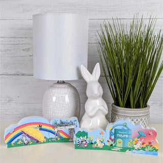Decorative items including a lamp, rabbit statue, plant, and Easter-themed cards on a surface.