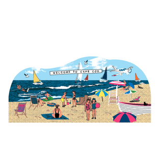 wooden replica with a design of a beach scene with people, umbrellas, and a boat, featuring 'Welcome to Cape Cod' text streaming from and airplane above the water