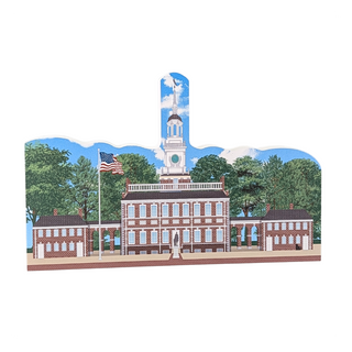 3/4" thick wooden cutout  of a building with a clock tower and American flag, set against a blue sky with clouds.