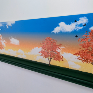 Scenic shelf of trees with autumn foliage, blue sky, and white clouds.