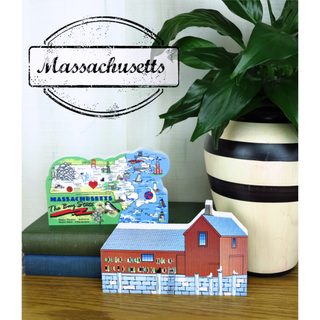 Massachusetts-themed decor items including a map and building model on books with a plant in the background.