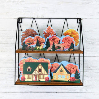 Decorative wall shelf with houses and trees on a white wooden background