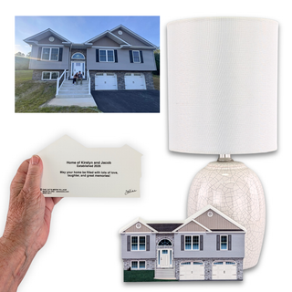A personalized home decor set featuring a custom printed lamp with a textured white shade and a crackled ceramic base, a matching house-shaped greeting card held by a hand, and a printed house graphic. The top-left inset shows the original reference photo of a gray two-car garage house.