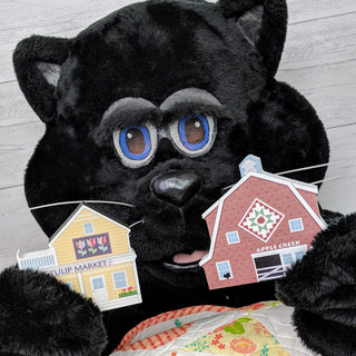 Black cat holding two 3/4" thick wooden illustrations of buildings