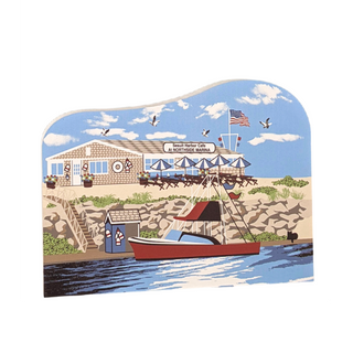 Wooden replica of a illustrated coastal scene with a building, boat, and American flag.