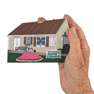 Hand holding a 3/4" wooden miniature house with a 'Smitty's Ice Cream' sign on a white background