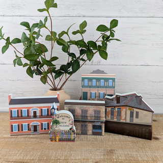 3/4" thick wooden model buildings of New Orleans with a plant on a wooden surface