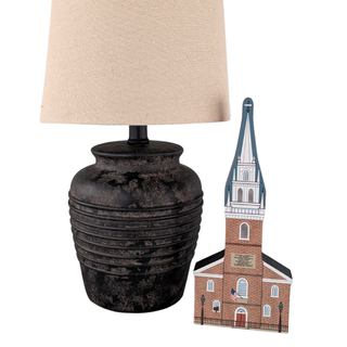 Table lamp with textured base and beige shade next to a 3/4" thick wooden model of the Old North Church in Boston.