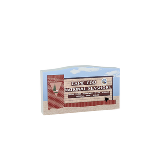 Wooden replica of a Cape Cod National Seashore sign with a brick wall and sky background.