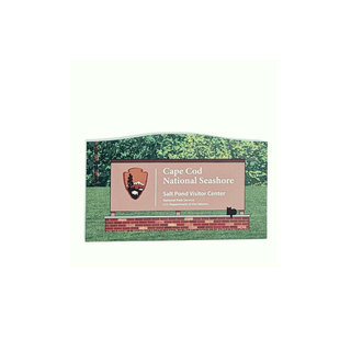 Wooden replica Cape Cod National Seashore sign with greenery in the background